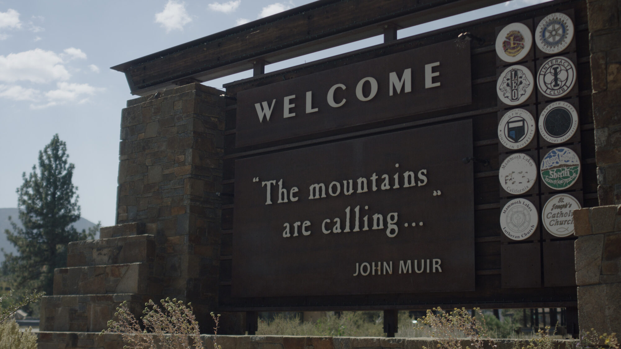 Welcome sign at the edge of the mountains reading The mountains are calling